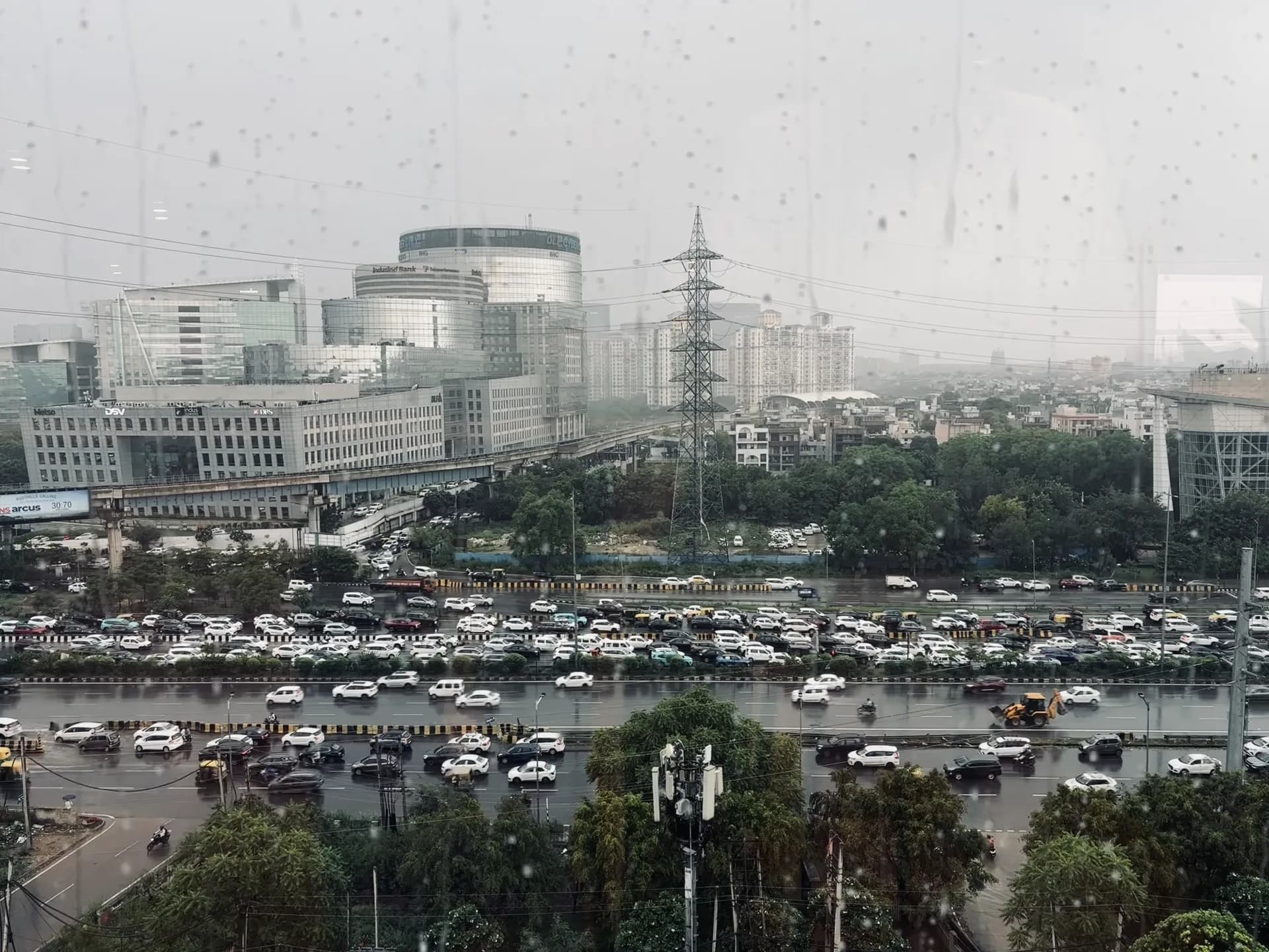 Monsoon rain on an office window overlooking a jammed highway and glass towers